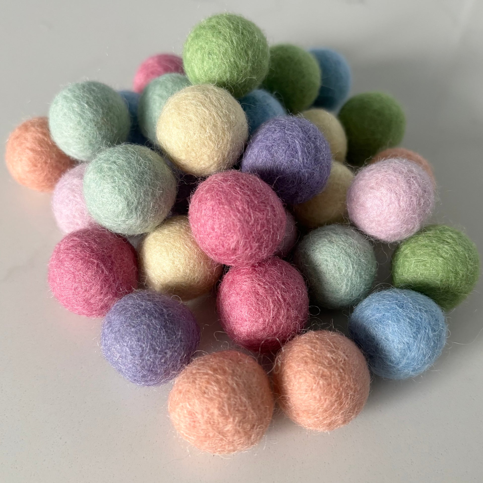 Assorted pastel colored felt balls on a white background